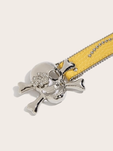 Detail van gele punkriem met zilveren schedelgesp, strass-steentjes en krokodillentextuur