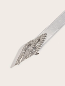 Close-up detail of silver belt buckle with sparkling rhinestones in a modern streamlined design