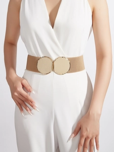 Detail eines khakifarbenen elastischen Gürtels mit runder goldener Schließe am weißen Kleid