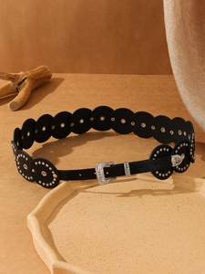 Detail of vintage black leather belt with silver floral carved buckle and metallic studs