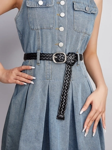 Close-up of black woven leather belt with silver buckle on light blue denim dress