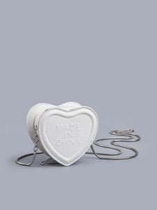 Macro detail of white heart-shaped mini bag with embossed texture and silver chain