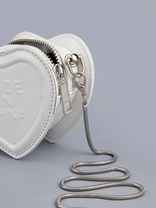 Detail of a white heart-shaped mini bag with silver chain and side zipper detail