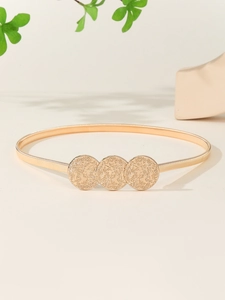 Detailed macro view of gold elastic spring belt with three embossed round metal buckles