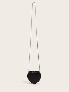 Detail view of heart-shaped mini crossbody bag with silver snake chain on beige background