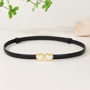 Détail d'une ceinture en cuir verni noir avec boucle dorée et motifs de cœur en perle