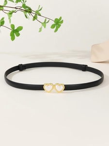 Détail d'une ceinture fine en cuir PU noir avec boucle double cœur dorée et perles