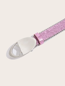 Détail d'une ceinture rose à paillettes avec perles argentées et grande boucle ovale