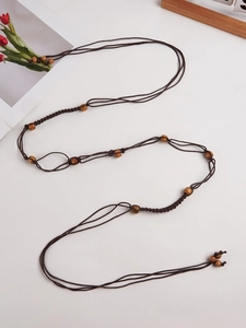 Gros plan sur la ceinture bohème tressée marron avec perles en bois naturel