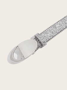 Détail de la ceinture à paillettes argentées avec bords perlés et boucle ovale ajourée