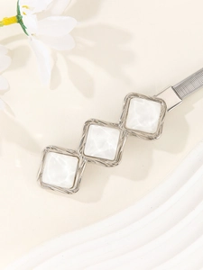 Detailed close-up of elastic silver snake chain belt with square white inlay buckle