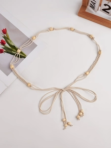 Détail d'une ceinture bohème tressée beige avec perles en bois et pompons pour robes