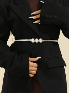 Gros plan d'une ceinture élastique en métal argenté avec perles sur un blazer