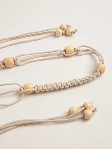 Détail d'une ceinture bohème en macramé avec tissage en coton et perles en bois naturel
