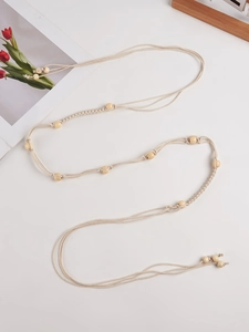 Détail d'une ceinture bohème en coton tissé avec perles en bois naturel et pompons