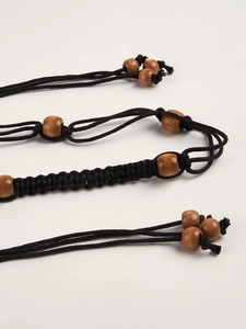 Détail de la ceinture tressée main avec cordons foncés et perles en bois naturel