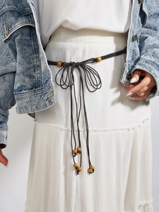 Détail d'une corde de taille tissée noire bohème avec des perles en bois sur robe