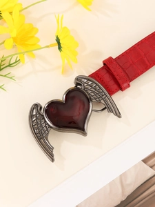 Detail of red crocodile texture belt featuring a silver heart-wing buckle in Y2K style