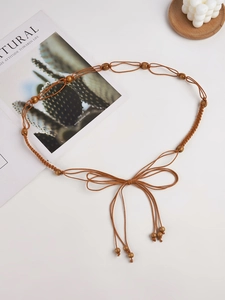 Détail de la chaîne de taille bohème tressée marron avec perles en bois et nœud papillon
