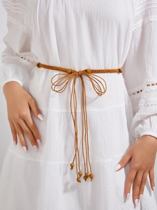 Détail d'une ceinture tressée bohème marron avec perles en bois et glands sur robe
