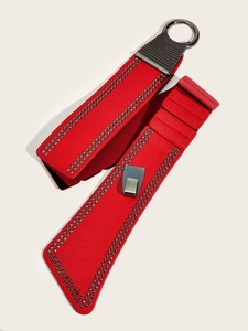 Détail de la ceinture corset en cuir rouge avec clous carrés argentés et franges en chaîne