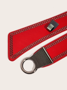 Détail d'une ceinture punk rouge avec clous carrés et grande boucle métallique ronde