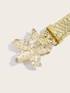 Macro shot of a luxury gold belt with a large 3D floral buckle and embossed texture