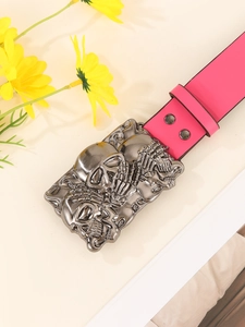Detail van felroze punk riem met zilveren gesp met 3 schedels en metalen studs
