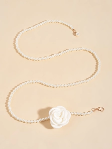 Close-up of pearl waist chain featuring a white satin rose and golden lobster clasp