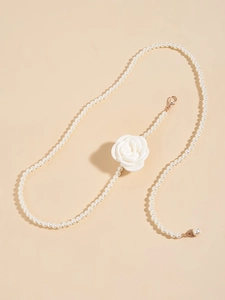 Detail of elegant white pearl waist chain featuring a large fabric rose and gold clasp