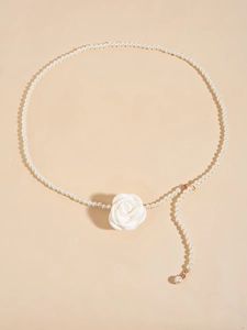 Detail of beaded pearl waist chain featuring a central white fabric rose and metal clasp