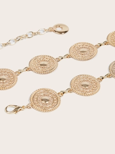 Close-up of golden metal waist chain featuring sunburst embossed circular medallions