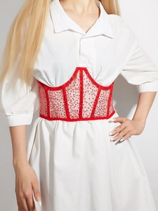 Detail of red sequined corset belt with fishbone support over a white dress