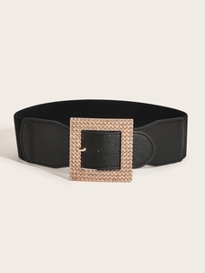 Close-up of a wide black elastic belt featuring a luxurious gold buckle with sparkling rhinestones