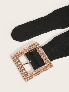 Close-up of a wide black leather belt with a large rose gold square buckle and rhinestones