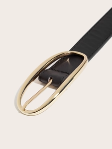 Détail de l'élégante boucle dorée ovale sur fine ceinture noire en cuir pour femme