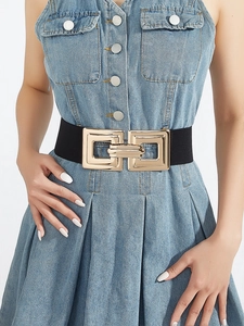 Détail de la ceinture élastique noire avec boucle géométrique dorée sur robe