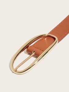 Gros plan sur une ceinture en cuir marron avec boucle ovale dorée et coutures de précision
