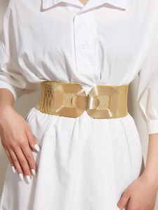 Detailed macro view of a gold geometric metal buckle on an embossed snakeskin elastic belt