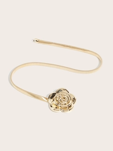 Detailed view of elegant gold metal rose buckle on a flexible elastic spring waist belt