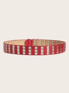 Detail of red punk belt featuring triple rows of silver metal eyelets and a classic pin buckle