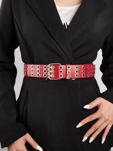Close-up of a red punk leather belt featuring triple rows of silver metal eyelets