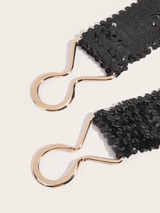 Close-up of black sequined belt featuring decorative interlocking golden metal buckles