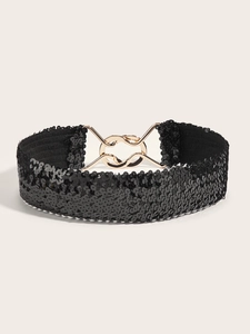 Detail of black sequin wide belt with a golden metal buckle on a neutral background
