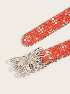 Détail d'une ceinture en tissu orange avec paillettes argentées et boucle papillon en métal