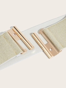 Detail of wide elastic waist belt featuring a gold mirror finish buckle and woven fabric