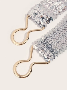 Macro detail of sparkling silver sequin belt featuring polished gold metal clasp hooks