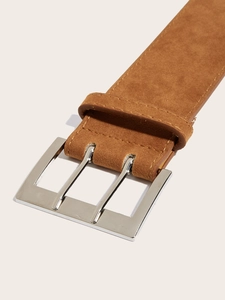 Close-up of brown suede belt with polished silver double-prong buckle and neat stitching