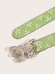Détail de la ceinture en denim vert clair avec boucle papillon argentée et sequins brillants