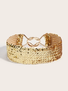 Detailed macro view of sparkling gold sequins and metal interlocking buckle on elastic belt